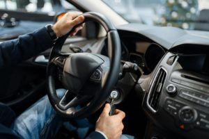 Male person behind the wheel of new automobile